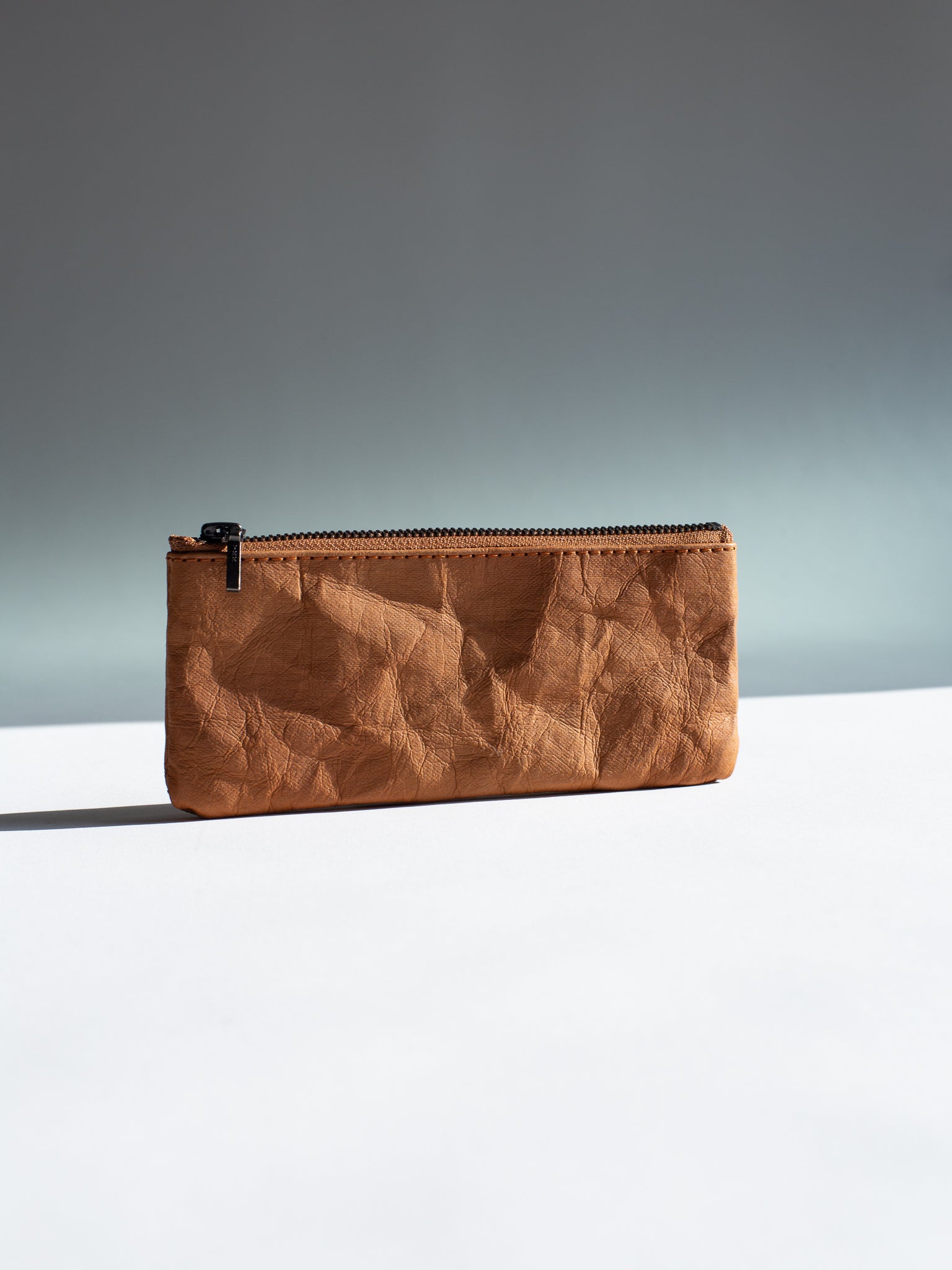Langackerhäuslの草木染めペンシルケース（Tabakカラー）。特殊加工紙のマットな質感と、乾燥した煙草の葉のような深いブラウンが調和する、オーストリア製ハンドメイドケース。